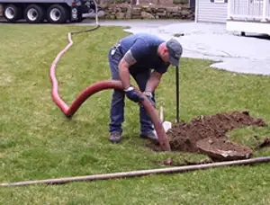Septic pumping technician servicing a residential septic tank with a vacuum hose in Atlanta, GA