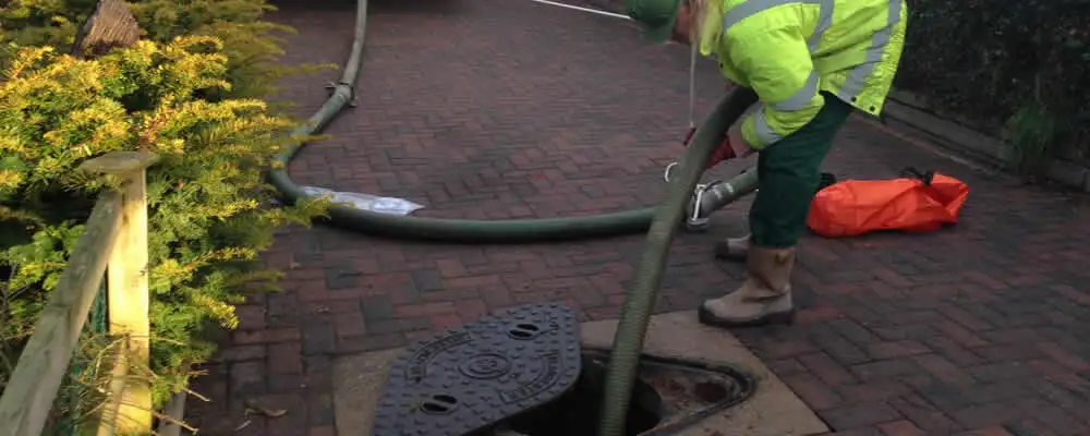 Septic tank cleaning technician servicing a septic tank with a vacuum hose in Atlanta, GA