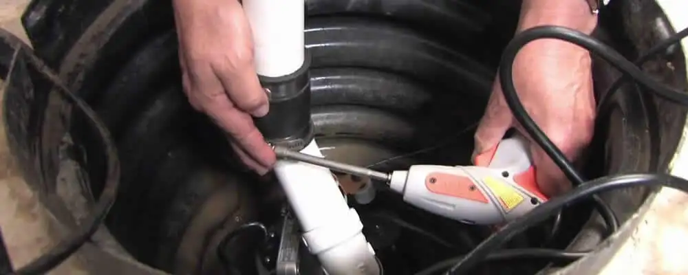 Sump pump installation technician connecting PVC discharge piping in Atlanta, GA